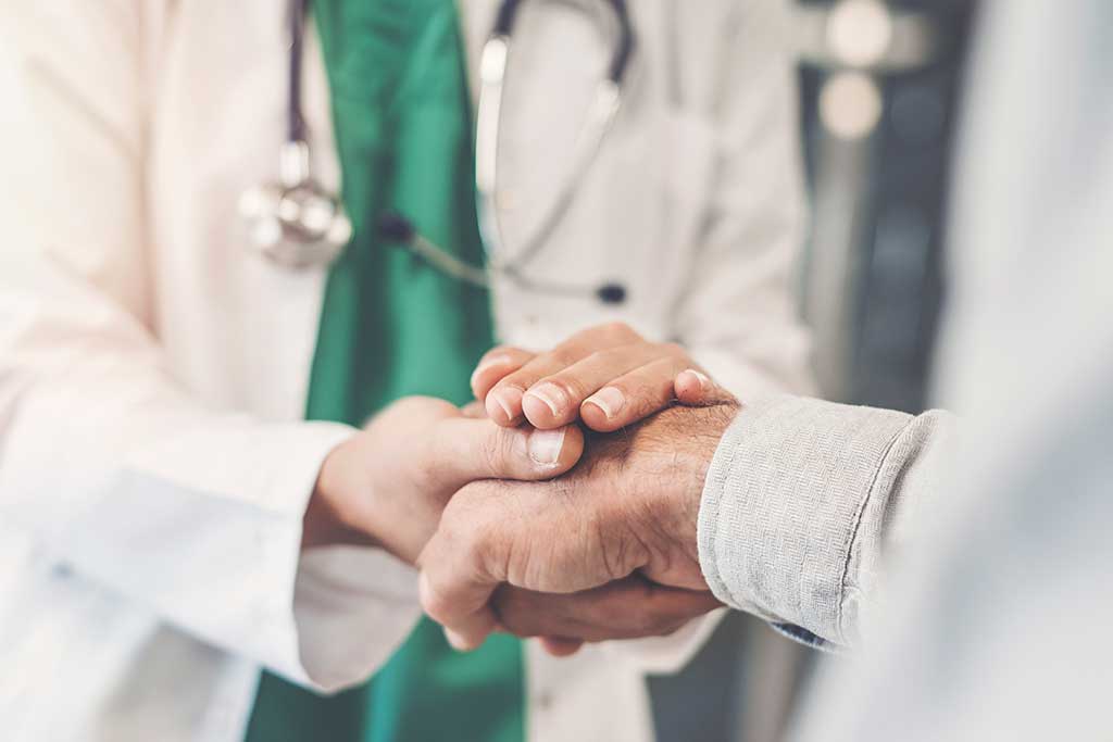 Physician in white coat shaking patient's hand